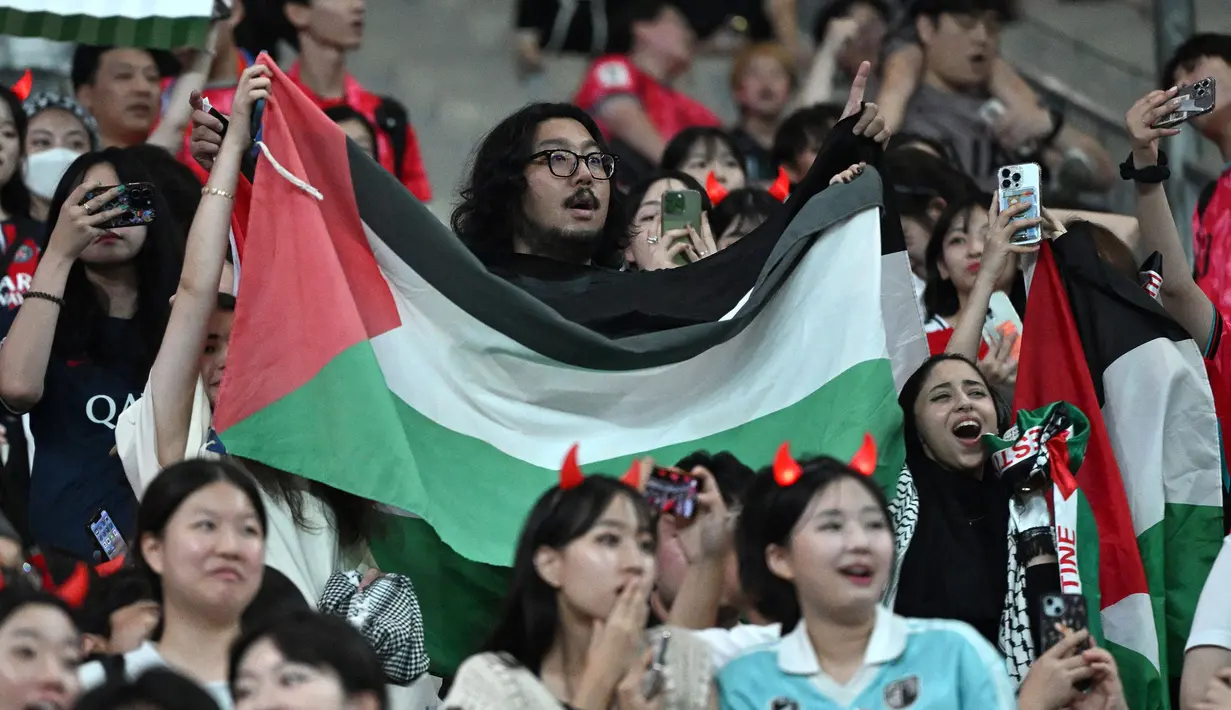Seorang suporter membentangkan bendera Palestina saat laga Grup B Kualifikasi Piala Dunia 2026 antara Korea Selatan melawan Palestina di Seoul World Cup Stadium, Seoul, Korea Selatan, Kamis (05/09/2024) WIB. (AFP/Jung Yeon-je)