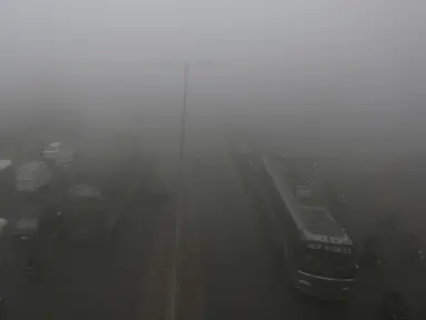 Kendaraan melaju lambat saat kabut tebal menyelimuti Lahore, Pakistan, 15 Desember 2021. Kabut tebal membuat kendaraan harus melaju lambat karena jarak pandang berkurang. (AP Photo/K.M. Chaudary)