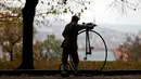 Seorang peserta mengenakan kostum sejarah mendorong sepeda penny farthing sebelum balapan penny farthing tahunan dimulai di Praha, Republik Ceko (5/11). (Reuters/David W Cerny)