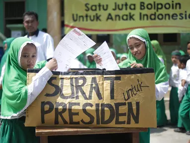 Murid Madrasah Ibtidayah (MI) Yayasan Nurul Bahri memasukan surat yang telah ditulis untuk Presiden Jokowi, di perkampungan nelayan Muara Angke, Jakarta, Senin (27/2). Gerakan Ayo Menulis ini digagas Standarpen Industries. (Liputan6.com/Faizal Fanani)