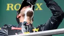 Selebrasi konyol, pembalap Red Bull Daniel Ricciardo saat merayakan keberhasilannya naik podium pada Grand Prix Formula 1 Jerman, Minggu (31/7). Ricciardo yang menjadi juara kedua meminum sampanye menggunakan sepatunya. (Patrik STOLLARZ / AFP)