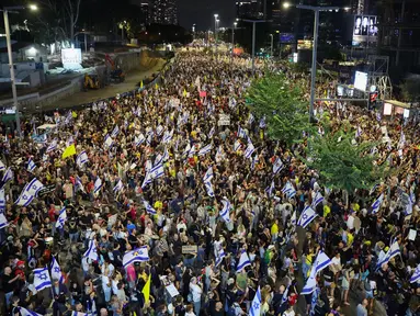 Para pengunjuk rasa mengangkat bendera dan plakat dalam unjuk rasa anti-pemerintah yang menuntut pembebasan warga Israel yang disandera oleh militan Palestina di Gaza sejak Oktober, di depan Kementerian Pertahanan Israel di Tel Aviv pada 14 September 2024. (Jack GUEZ/AFP)