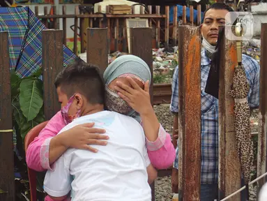 Seorang ibu memeluk anaknya saat aksi mencuci kaki ibu secara massal di Kelurahan Duri Pulo, Jakarta, Rabu (21/12/2021). Aksi yang diikuti 500 peserta ini bertujuan meningkatkan rasa cinta kasih kepada ibu dan dilakukan dalam rangka memeriahkan Hari Ibu. (Liputan6.com/Herman Zakharia)