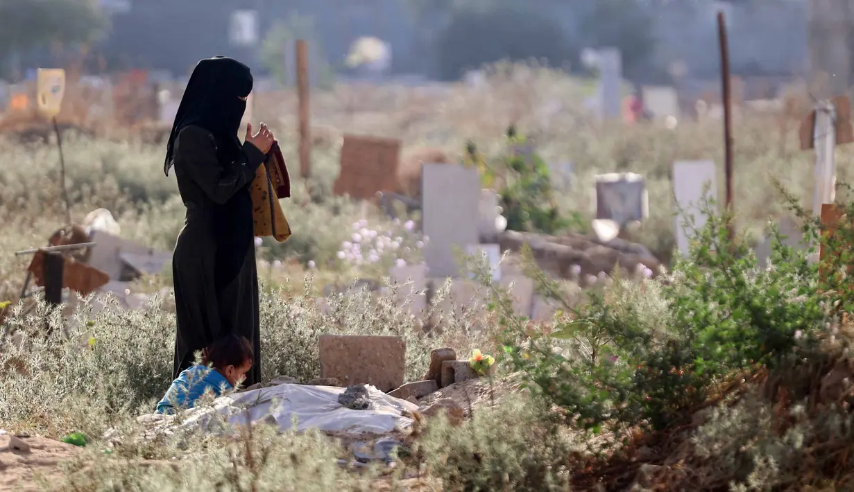 Seorang wanita Palestina berdoa di dekat makam seorang kerabatnya yang menjadi korban dalam konflik yang sedang berlangsung antara Israel dan milisi Hamas, di sebuah pemakaman darurat di lingkungan al-Tuffah timur Kota Gaza, pada 16 Juni 2024. (Omar AL-QATTAA/AFP)