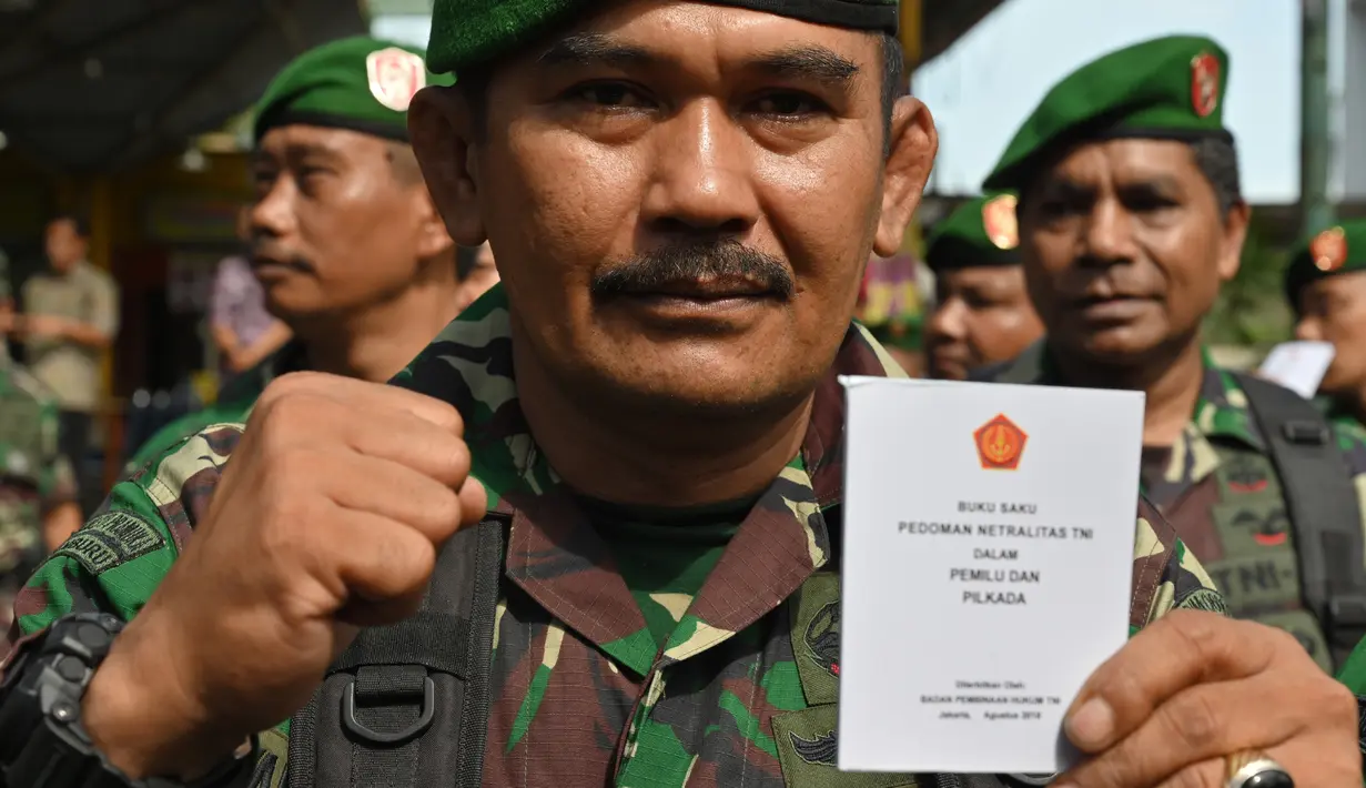 Seorang tentara menunjukkan buku pedoman netralitas untuk anggota militer saat apel pengamanan Pemilu 2019 di Bogor, Jawa Barat, Rabu (10/4). TNI-Polri menyatakan siap mengamankan masyarakat sampai ke TPS hingga pesta demokrasi selesai. (ADEK BERRY/AFP)