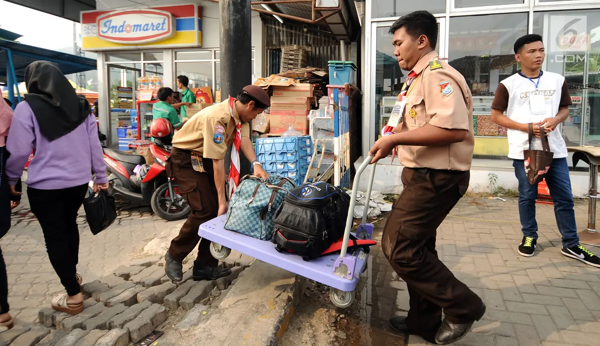 Anggota Pramuka mengangkat troli dan barang bawaan pemudik di kawasan Pelabuhan Merak, Banten, Kamis (22/6). Di Pelabuhan Merak, sejumlah anggota Pramuka diterjunkan untuk membantu pemudik membawa barang bawaan. (Liputan6.com/Helmi Fithriansyah)