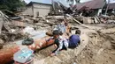 Hingga kini, tim gabungan dari BPBD, TNI, Polri, Basarnas, dan relawan terus melakukan pencarian terhadap warga yang masih hilang. Tampak dalam foto, anak-anak bermain di dekat rumah-rumah yang rusak di sebuah desa yang terdampak banjir bandang di Batang Toru, Sumatera Utara, Senin 1 Desember 2025. (AP Photo/Binsar Bakkara)
