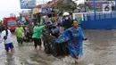 Pengendara bersama sepeda motornya berada di atas gerobak yang didorong pengojek gerobak saat melintasi banjir yang merendam jalan KH Hasyim Ashari, Kota Tangerang, Banten, Sabtu (16/7/2022). Warga sekitar membantu para pengendara yang melintas agar tidak terkena banjir dengan menawarkan jasa gerobak. (Liputan6.com/Angga Yuniar)