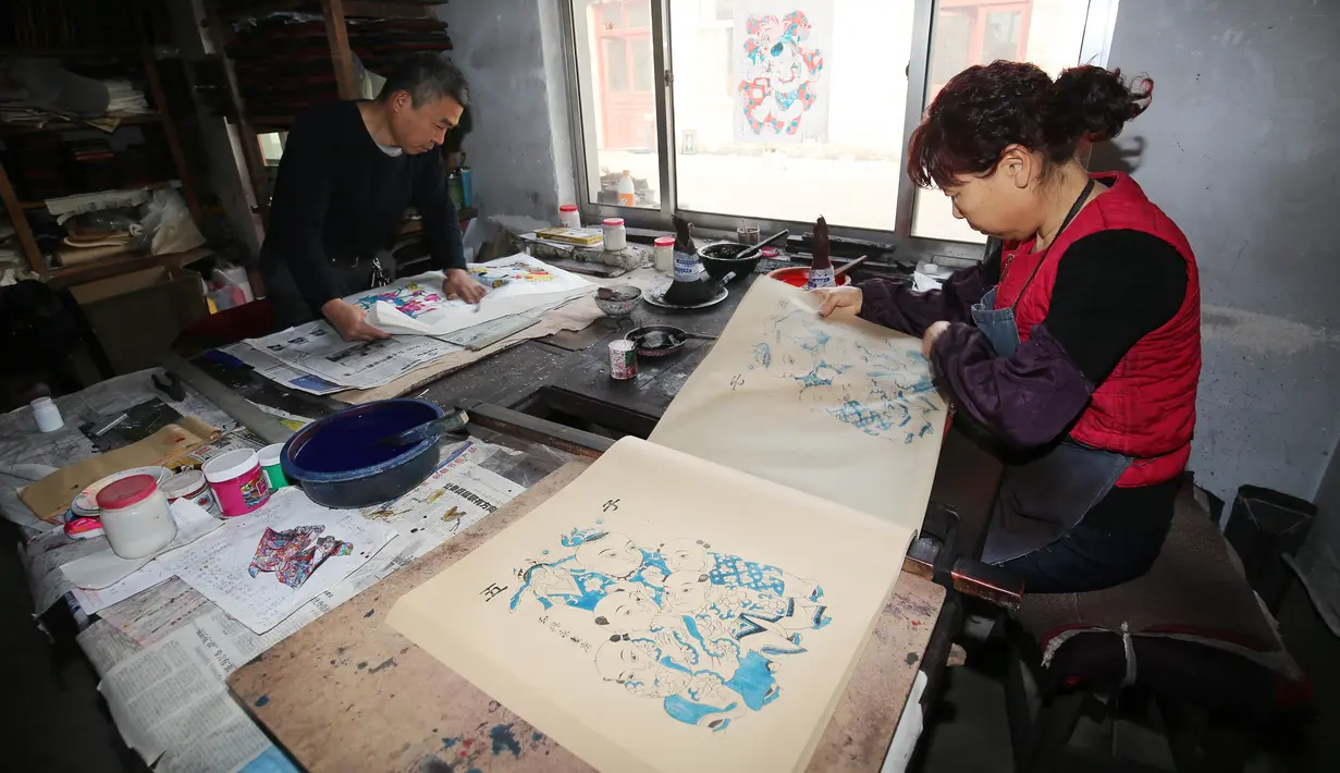 Pekerja menyelesaikan pembuatan gambar untuk tahun baru Imlek di sebuah lokakarya di Weifang di provinsi Shandong, Tiongkok (20/1). Mereka membuat gambar untuk perayaan Imlek ini secara manual. (AFP)