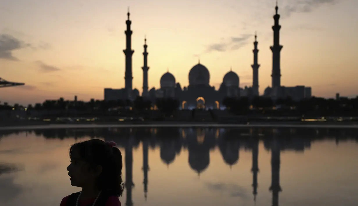 Seorang gadis bermain di depan sebuah kolam saat matahari terbenam di belakang Masjid Agung Sheikh Zayed di Abu Dhabi, Uni Emirat Arab (8/11/2019). asjid ini dibangun oleh presiden pertama Uni Emirat Arab, yaitu Sheikh Zayed bin Sultan Al Nahyan. (AFP Photo/Kamran Jebreili)