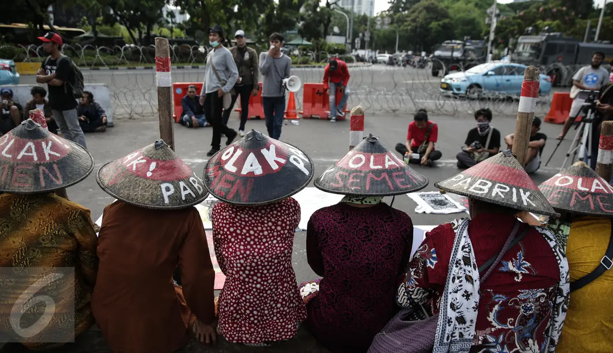 Sejumlah membawa lesung saat menggelar aksi di depan Istana Merdeka, Jakarta, Rabu (12/4). Mereka meminta Pemerintah untuk menghentikan pembangunan dan pabrik semen di Pegunungan Kendeng. (Liputan6.com/Faizal Fanani)