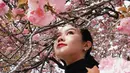 Rambut panjangnya dibiarkan diikat ke belakang, tertiup angin, menciptakan kesan natural namun tetap anggun. Riasan wajahnya pun tampak minimalis namun tetap memikat dengan pulasan lipstik merah yang menjadi statement tersendiri, membuat penampilannya semakin stand out di antara hamparan bunga sakura berwarna pink pastel. [@yurayunita].