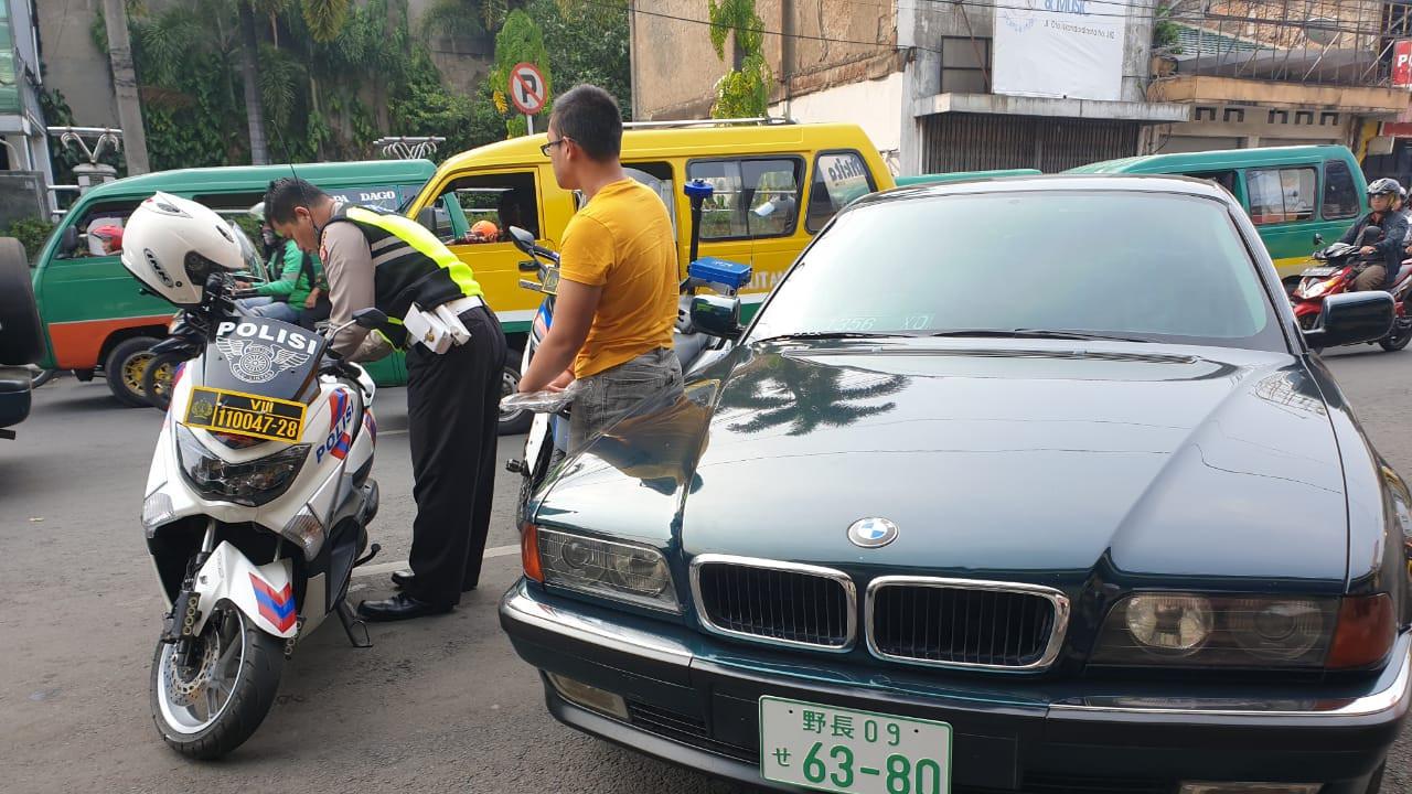 Polisi tilang pengendaran BMW yang menggunakan plat nomor Jepang.