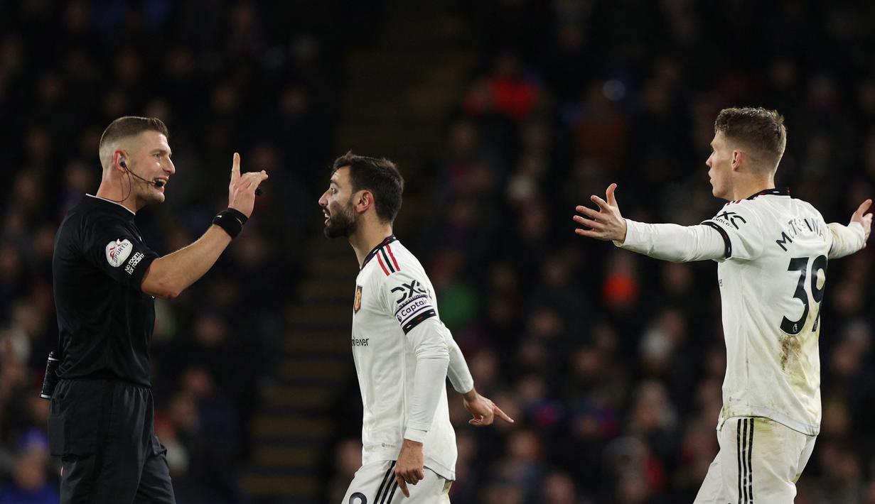 Pemain MU, Bruno Fernandes (tengah) melakukan protes kepada wasit, Robert Jones (kiri) setelah Scoot McTominay dilanggar pemain Crystal Palace di kotak penalti dalam pertandingan lanjutan Liga Inggris 2022/2023 yang berlangsung di Selhurst Park, London, Kamis (19/1/2023). (AFP/Adrian Dennis)