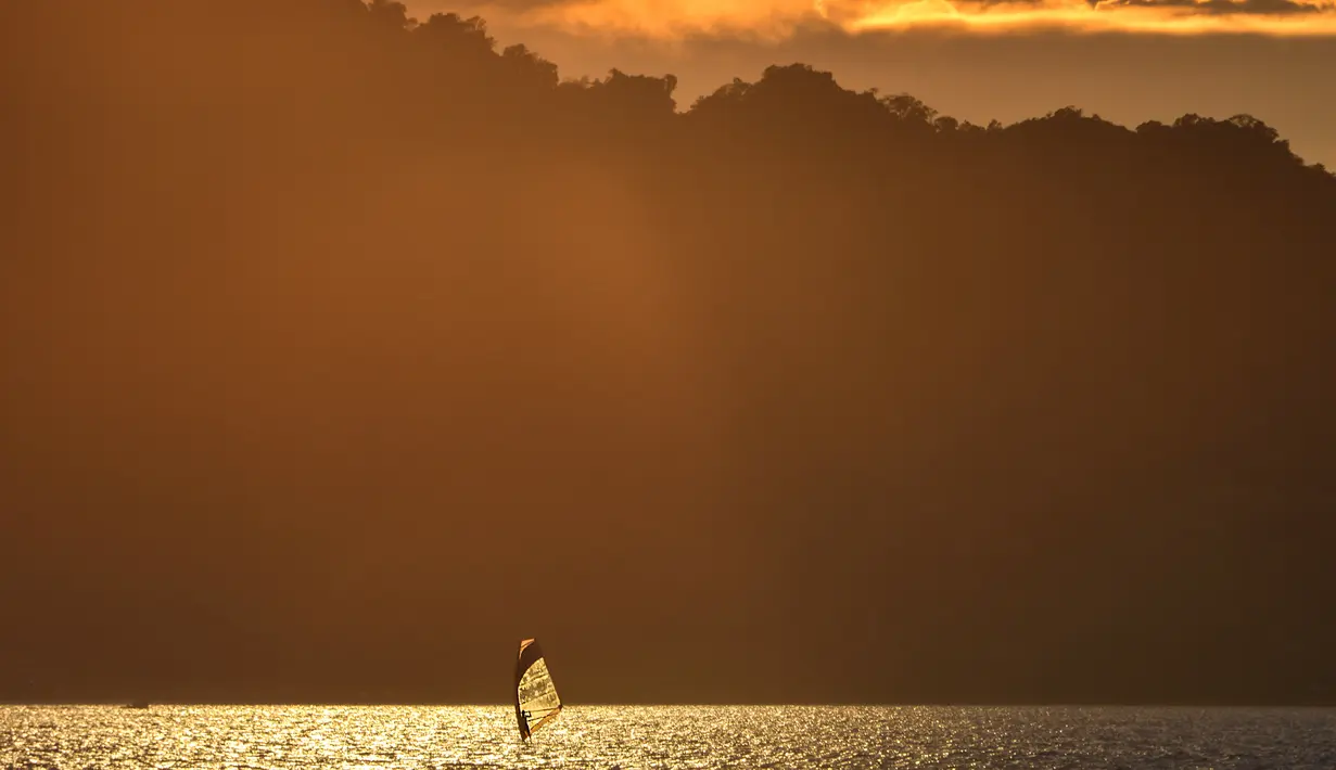 Seorang pria bermain selancar angin saat matahari terbenam di sebuah pantai di Banda Aceh (7/4). Kota Banda Aceh merupakan salah satu kota yang berada di Aceh dan menjadi ibukota Provinsi Aceh, Indonesia. (AFP Photo/Chaideer Mahyuddin)