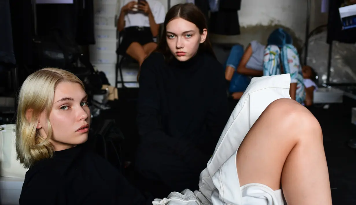 Dua model berpose di belakang panggung sebelum tampil mengenakan busana Women Spring/Summer 2019 karya Jil Sander selama Milan Fashion Week di Italia (19/9). (AFP Photo/Miguel Medina)