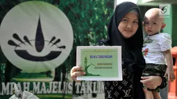 Warga menunjukkan buku tabungan Bank Sampah Majelis Taklim di Kecamatan Koja, Jakarta, Senin (15/7/2019). Sampah anorganik tersebut dapat ditukarkan dengan liburan ke tiga negara, yakni Malaysia, Singapura, dan Thailand. (merdeka.com/Iqbal S. Nugroho)