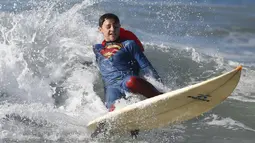 Peserta berselancar dengan mengenakan pakaian Superman selama ikuti lomba selancar di Santa Monica, Amerika Serikat, Sabtu (31/10/2015). Perlombaan ini mewajibkan peserta mengenakan kostum bertema Halloween. (REUTERS/Lucy Nicholson)