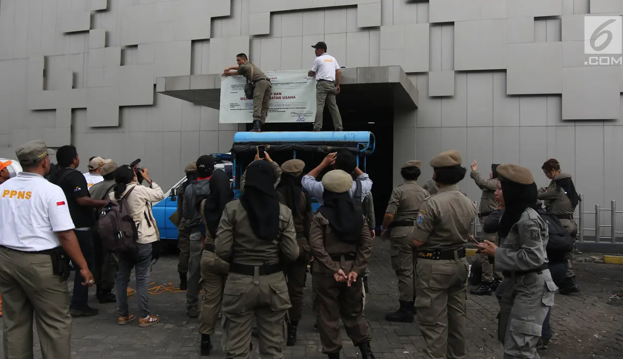 Petugas Satpol PP memasang banner penutup  saat menyegel Diskotek Exotic di Mangga Besar, Jakarta, Kamis (19/4). Exotic diberi batas waktu penutupan usaha hingga 18 April 2018, tapi mereka telah lebih dulu tutup 15 April 2018. (Liputan6.com/Arya Manggala)
