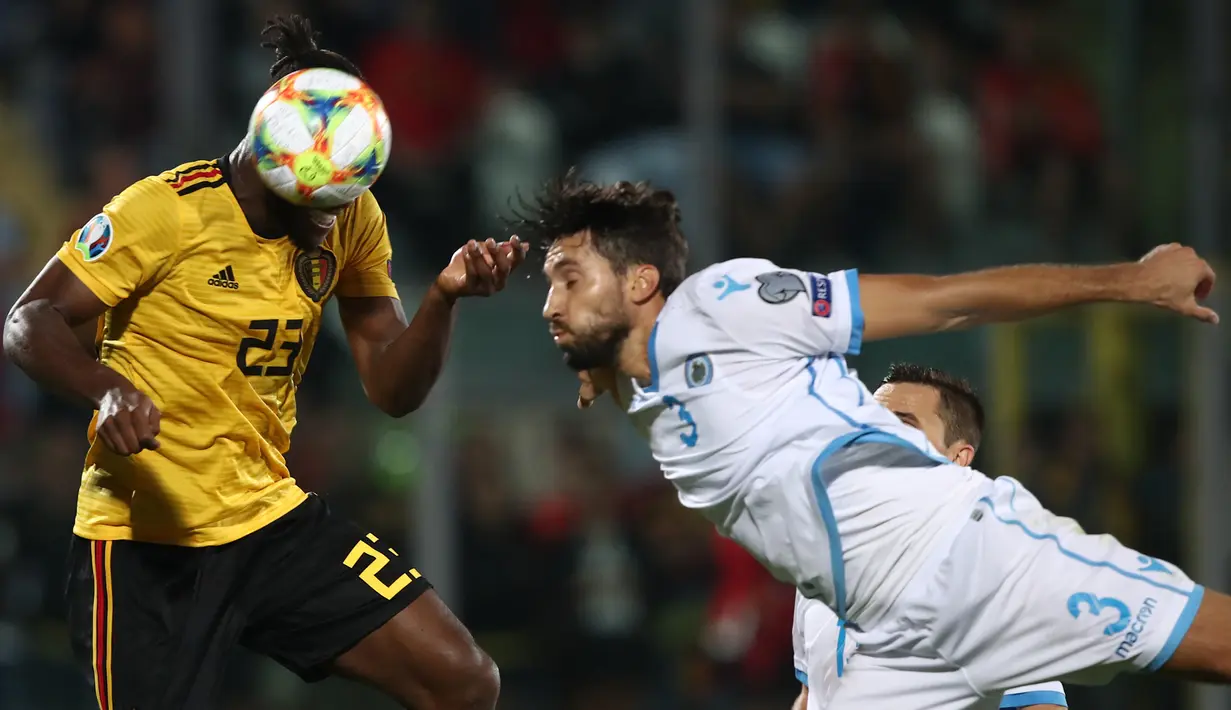 Striker Belgia, Michy Batshuayi, duel udara dengan bek San Marino, Mirko Palazzi, pada laga Kualifikasi Piala Dunia 2022 di Olympic Stadium, Serravalle, Jumat (6/9). San Marino kalah 0-4 dari Belgia. (AFP/Isabella Bonotto)
