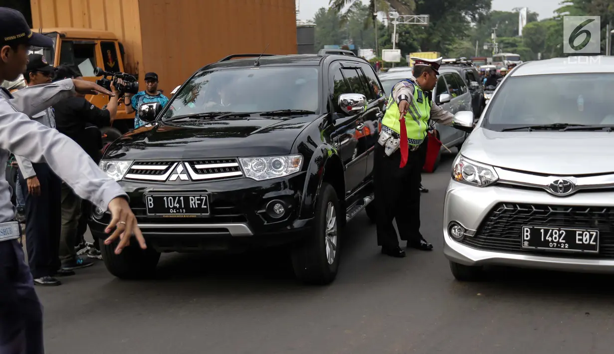 Petugas polisi lalu lintas memberhentikan kendaraan saat pemberlakuan sistem ganjil genap di pintu masuk Gardu Tol Cibubur 2, Jakarta, Senin (16/4). Aturan ini berlaku untuk kendaraan pribadi atau golongan I dan II. (Liputan6.com/Faizal Fanani)