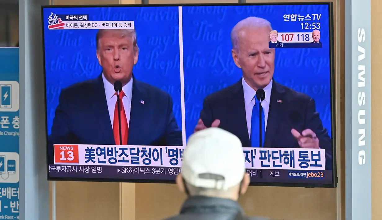 Seorang pria menonton program berita televisi tentang pemilihan presiden (pilpres) AS yang menampilkan gambar Presiden Donald Trump (kiri) dan calon presiden dari Partai Demokrat Joe Biden (kanan), di sebuah stasiun kereta api di Seoul, Korea Selatan, Rabu (4/11/2020). (Photo by Jung Yeon-je/AFP)