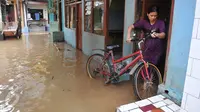 Warga memindahkan sepedanya menyusul surutnya air yang sempat merendam pemukiman mereka di kawasan Kampung Pulo, Kelurahan Kampung Melayu, Jatinegara, Jakarta, Selasa, (17/11). (Liputan6.com/Gempur M Surya)