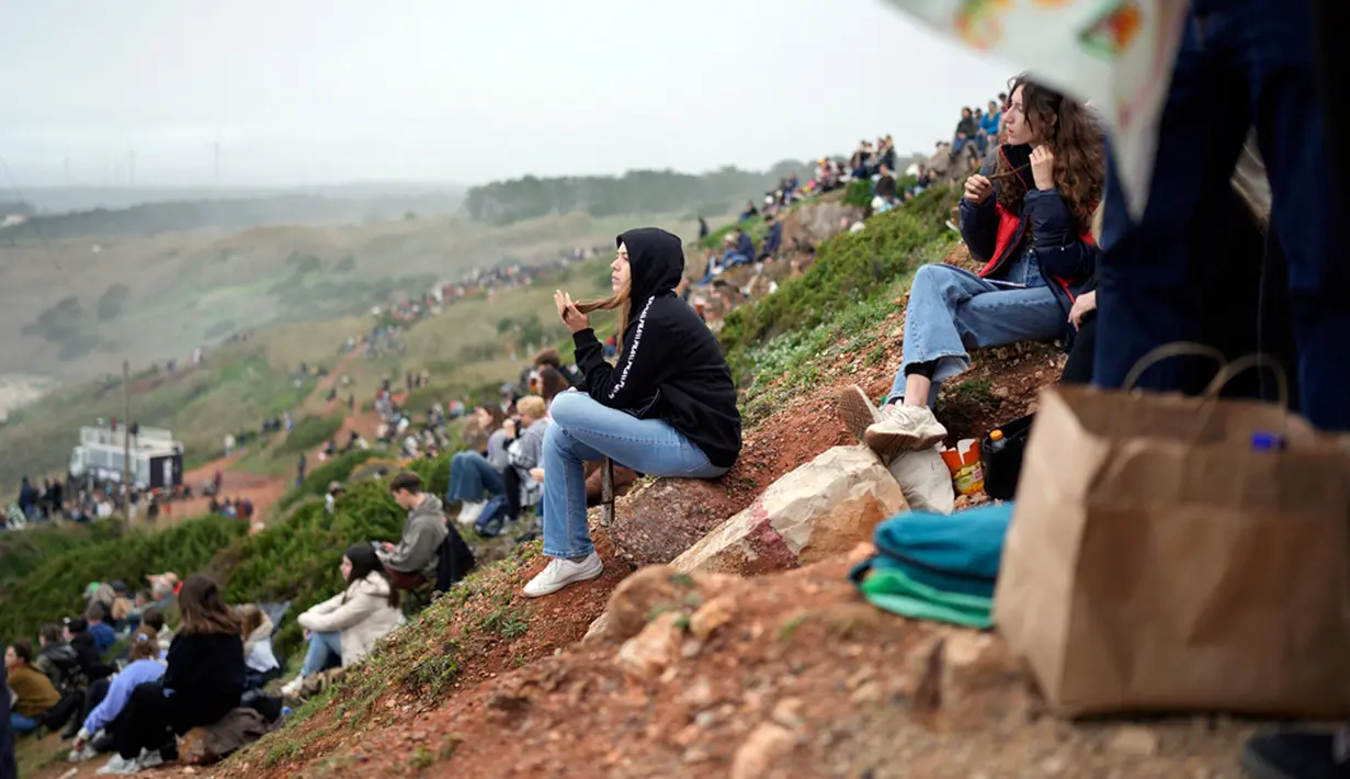 Penggemar selancar duduk di sepanjang tebing untuk menyaksikan para peselancar menaiki ombak selama turnamen selancar Nazare Big Wave Challenge. (AP Photo/Armando Franca)