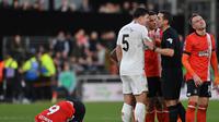 Wasit Inggris David Coote dikelilingi para pemain Luton Town dan Manchester United yang sedang melakukan protes. Tampak kapten tim MU, Harry Maguire. (GLYN KIRK / AFP)