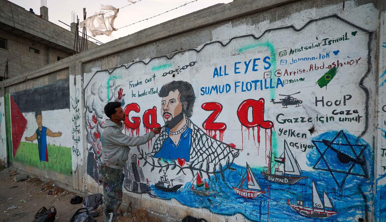 Seorang seniman Palestina melukis mural yang menggambarkan pencegatan kapal-kapal yang berpartisipasi dalam Armada Sumud Global, sebuah misi bantuan kemanusiaan yang dipimpin sipil ke Gaza melalui laut, di Nuseirat, Jalur Gaza Tengah pada 19 Mei 2026. (Eyad Baba/AFP)