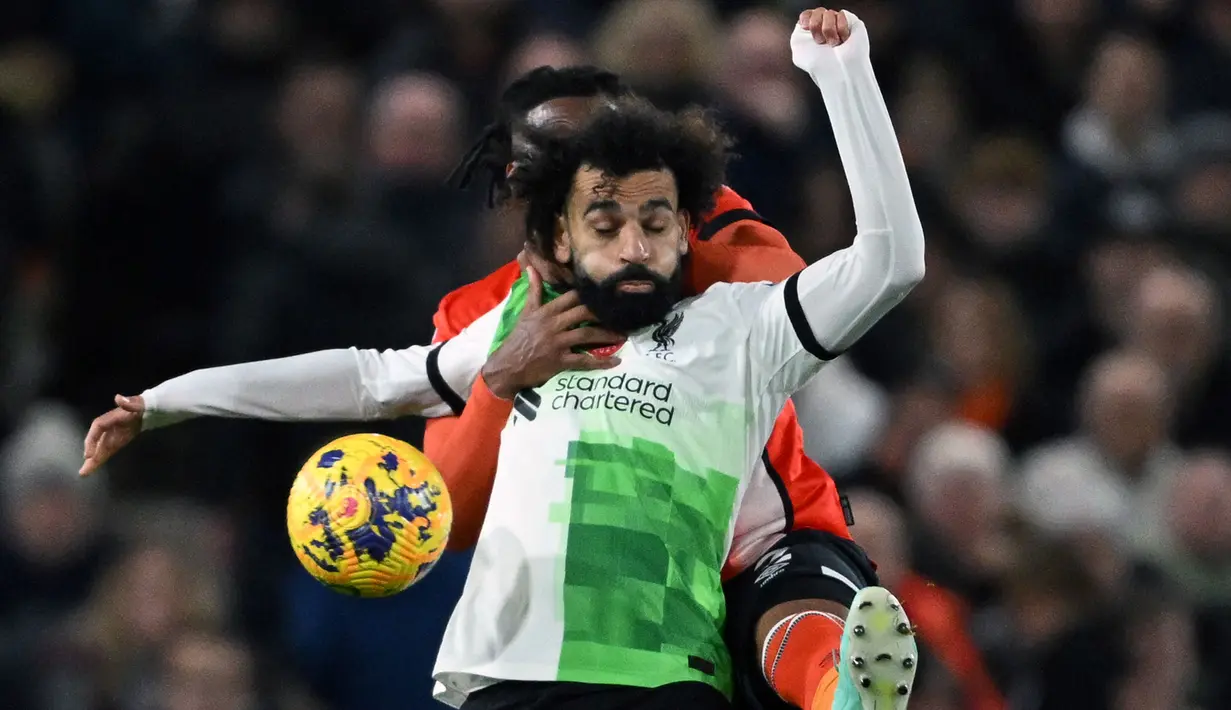 Striker Liverpool, Mohamed Salah (depan) berebut bola dengan bek Luton Town, Gabriel Osho pada laga pekan ke-11 Liga Inggris 2023/2024 di Kenilworth Road Stadium, London, Minggu (5/11/2023) malam WIB. (AFP/Justin Tallis)