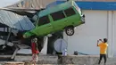 Warga mengambil foto mobil yang nyangkut di sebuah bangunan usai terjadinya gempa dan tsunami di pantai Talise di Palu, Sulawesi Tengah (1/10). Gempa dan tsunami yang melanda palu dan donggala menewaskan ratusan korban jiwa. (AP Photo/Tatan Syuflana)