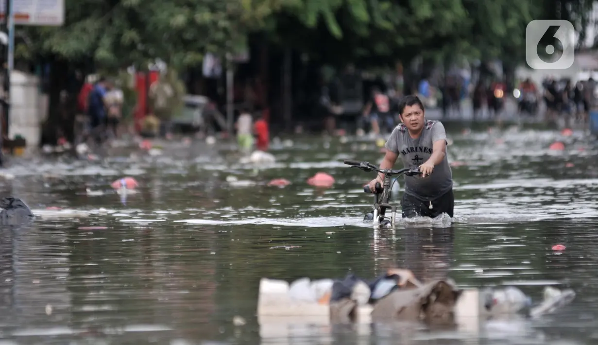 Warga menuntun sepeda saat melintasi banjir yang merendam Jalan RA Kartini, Bekasi, Jawa Barat, Kamis (2/1/2020). Banjir yang merendam Jalan RA Kartini sejak kemarin melumpuhkan akses kendaraan dan perekonomian warga setempat. (merdeka.com/Iqbal Nugroho)