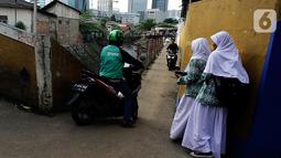 Pengendara sepeda motor melintasi jalur alternatif saat anak sekolah berjalan di belakang Kompleks Patra Jasa, Jakarta Selatan, Rabu (1/3/2023). (Liputan6.com/Johan Tallo)