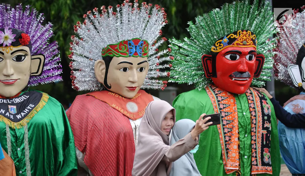 Warga berswafoto di depan deretan ondel-ondel di kawasan silang Monumen Nasional, Jakarta, Minggu (26/11). Deretan ondel-ondel ini bagian kemeriahan Kirab Kebangsaan yang diadakan Bamus Betawi. (Liputan6.com/Helmi Fithriansyah)
