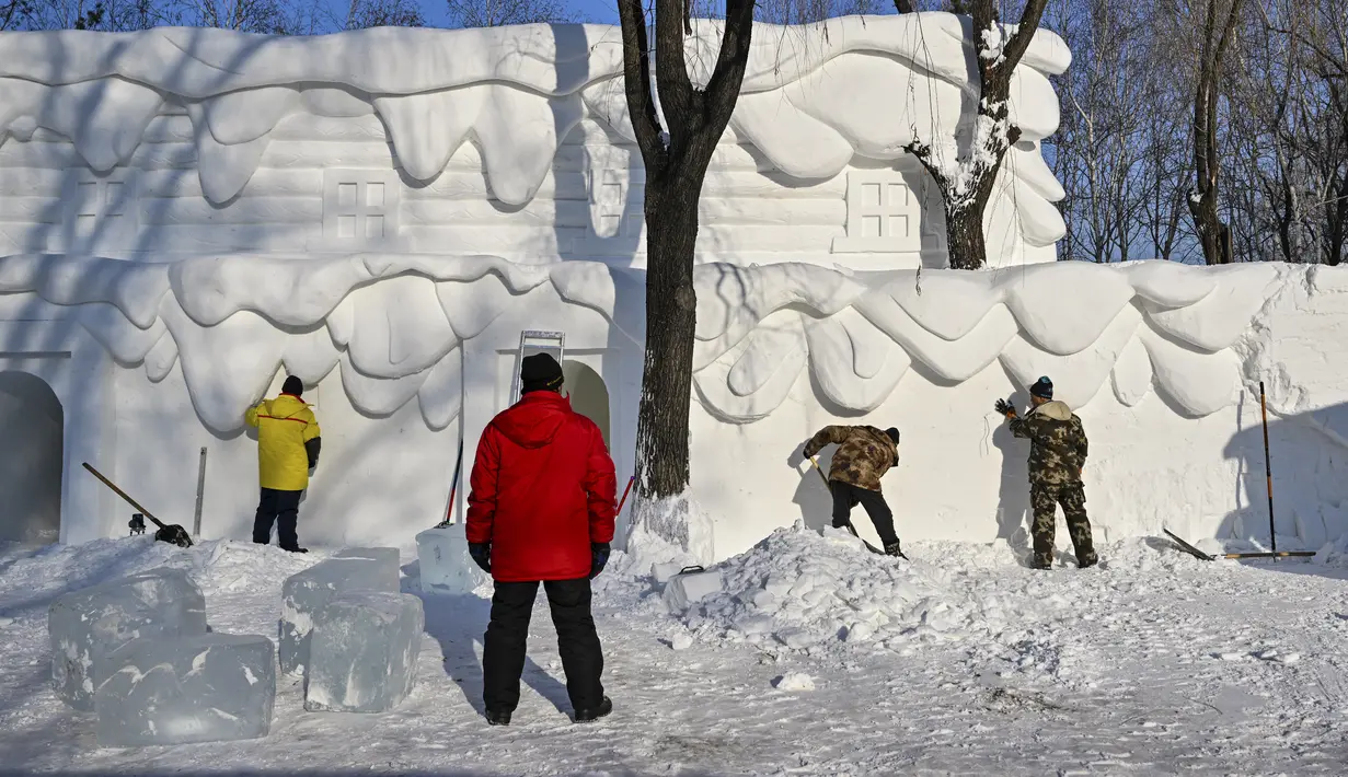 Para pria membangun rumah salju di Pameran Seni Patung Salju Internasional Harbin Sun Island menjelang Festival Es dan Salju Internasional Harbin Tiongkok ke-39 di Harbin, di provinsi Heilongjiang timur laut China (4/1/2023). (AFP/Hector Retamal)