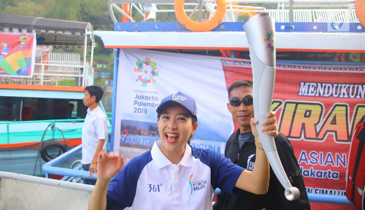 Artis Olivia Zalianty membawa obor Asian Games 2018 berkeliling Danau Toba di Sumatra Utara, Rabu (1/8). Obor Asian Games itu akan di bawa berlayar dengan kapal hias di Danau Toba dan bersepeda menuju pantai bebas Danau Toba. (Liputan6.com/Reza Perdana)
