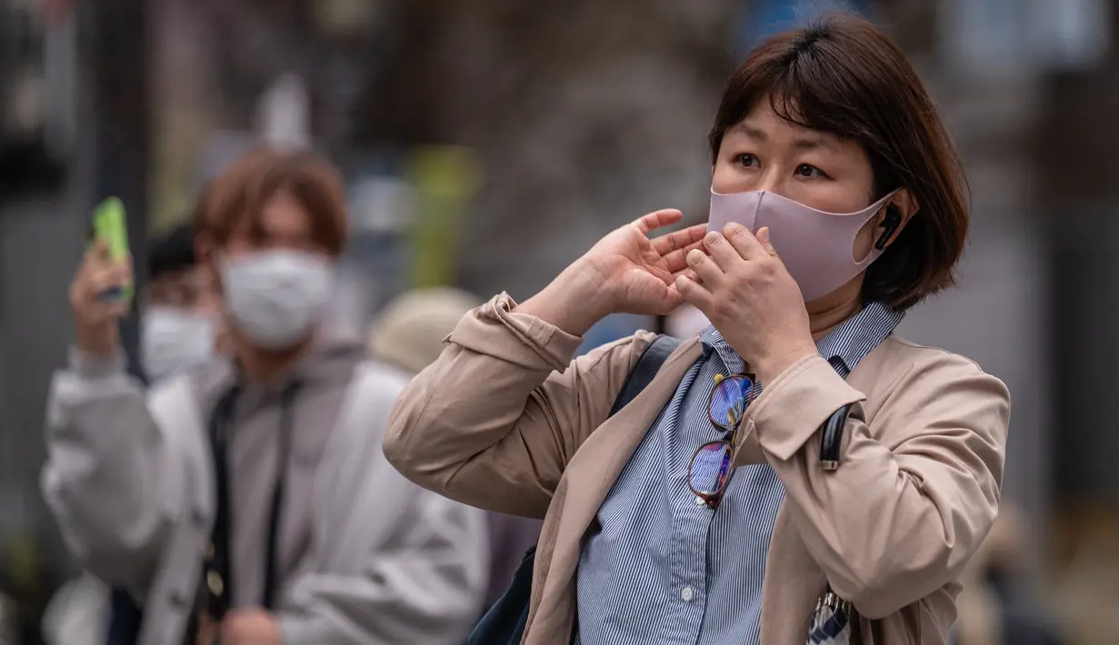 Orang-orang menyeberang jalan di distrik Shibuya Tokyo pada hari pertama pemerintah Jepang mencabut ketentuan wajib mengenakan masker, Senin (13/3/2023). Sebelumnya selama tiga tahun terakhir Jepang mewajibkan pemaikaian masker akibat pandemi Covid-19. (Photo by Yuichi YAMAZAKI / AFP)