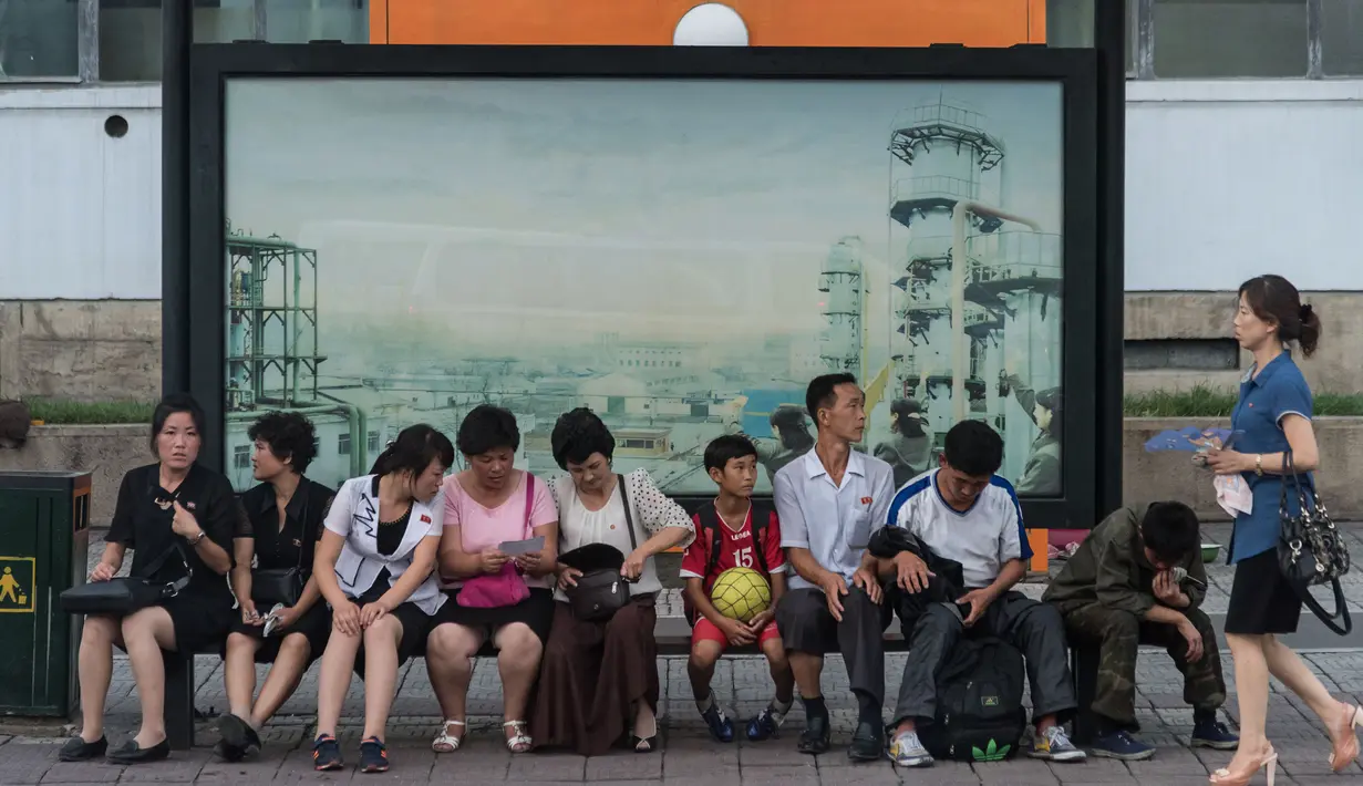 Foto yang diambil pada 28 Juli 2017 memperlihatkan sejumlah calon penumpang menunggu bus di sebuah halte di Pyongyang, Korea Utara. (Ed JONES/AFP)