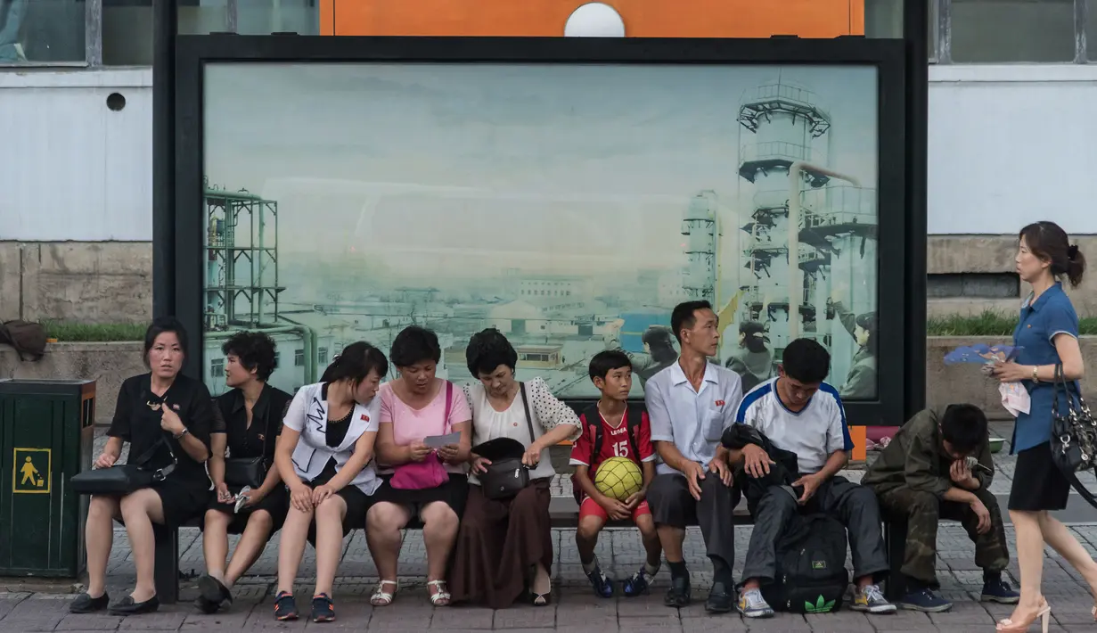 Foto yang diambil pada 28 Juli 2017 memperlihatkan sejumlah calon penumpang menunggu bus di sebuah halte di Pyongyang, Korea Utara. (Ed JONES/AFP)