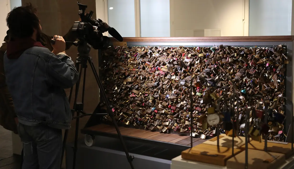 Awak media mengambil gambar gembok cinta dari Jembatan Pont des Art saat dilelang oleh Ville de Paris, Prancis, Rabu (3/5). Penjualan dari lelang itu diharapkan akan mengumpulkan uang hingga 107.250 dolar untuk pengungsi di Paris. (Jacques DEMARTHON/AFP)