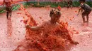 Seorang anak melompat ke dalam kolam berisi tomat selama Festival Tomat di Hwacheon, Korea Selatan, 5 Agustus 2017. Di festival ini, pengunjung bebas memetik tomat yang siap dipanen, membuat saus tomat, dan mandi tomat. (AP Photo/Ahn Young-joon)