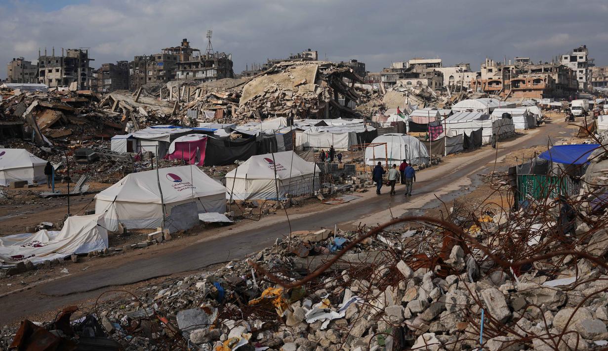 Sebagai informasi, menurut catatan Kementerian Kesehatan di Gaza hingga 27 Desember 2025, serangan Israel di Gaza telah menewaskan lebih dari 71.266 orang dan melukai lebih dari 171.200 lainnya. Serangan Israel di Gaza juga menghancurkan infrastruktur sipil dan melumpuhkan sistem layanan dasar. Tampak dalam foto, warga Palestina berjalan di sepanjang jalan melewati perkemahan tenda yang dikelilingi bangunan-bangunan yang hancur akibat serangan udara dan darat Israel di lingkungan Sheikh Radwan, Kota Gaza, Selasa, 30 Desember 2025. (AP Photo/Abdel Kareem Hana)