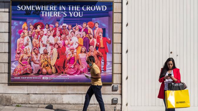 Orang-orang berjalan melewati sebuah reklame di West End, London, Inggris, pada 21 September 2020. Menteri Kesehatan Matt Hancock pada Minggu (20/9) mengatakan Inggris sedang menghadapi 