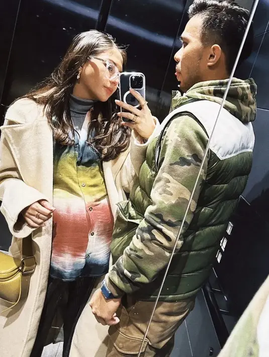 Berfoto bersama sang suami, Jessica Mila mengenakan coat beige sebagai luaran dipadukan inner kemeja colorful dan turtle neck abu-abunya.  [@jscmila]