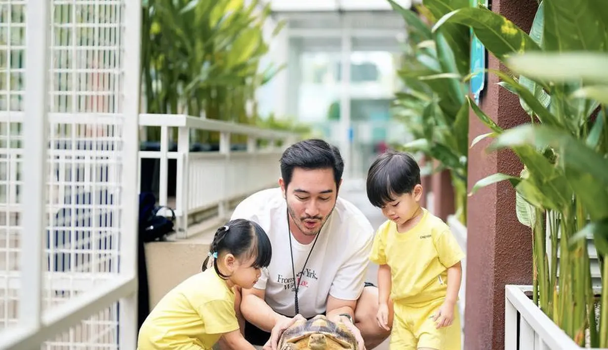 Saat bermain bersama kedua anak kembarnya, Jeje tampil santai dengan kaos putih dipadukan celana pendek serta mengenakan aksesori kalungnya. (@ritchieismail)