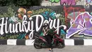 Pengendara berhenti di jalur inspeksi Sungai Ciliwung, Jakarta, Kamis (27/12). Mural yang dibuat oleh beberapa komunitas tersebut menjadikan jalur inspeksi Sungai Ciliwung tampak lebih berwarna dan asri. (Liputan6.com/Immanuel Antonius)