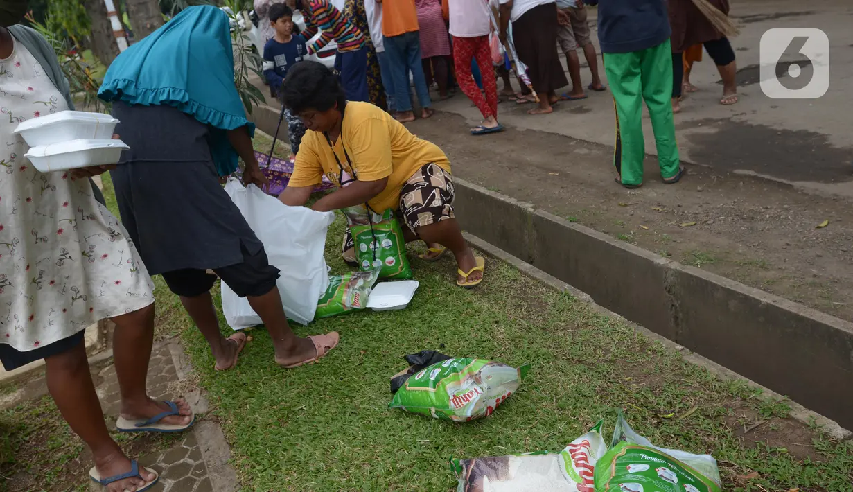 Warga menata sembako yang didapatkannya di TPU Malaka, Pondok Kopi, Jakarta, Jumat (4/3/2022). Pembagian sejumlah sembako secara gratis yang diperuntukan bagi kaum duafa ini berupa beras dan minyak goreng. (merdeka.com/Imam Buhori)