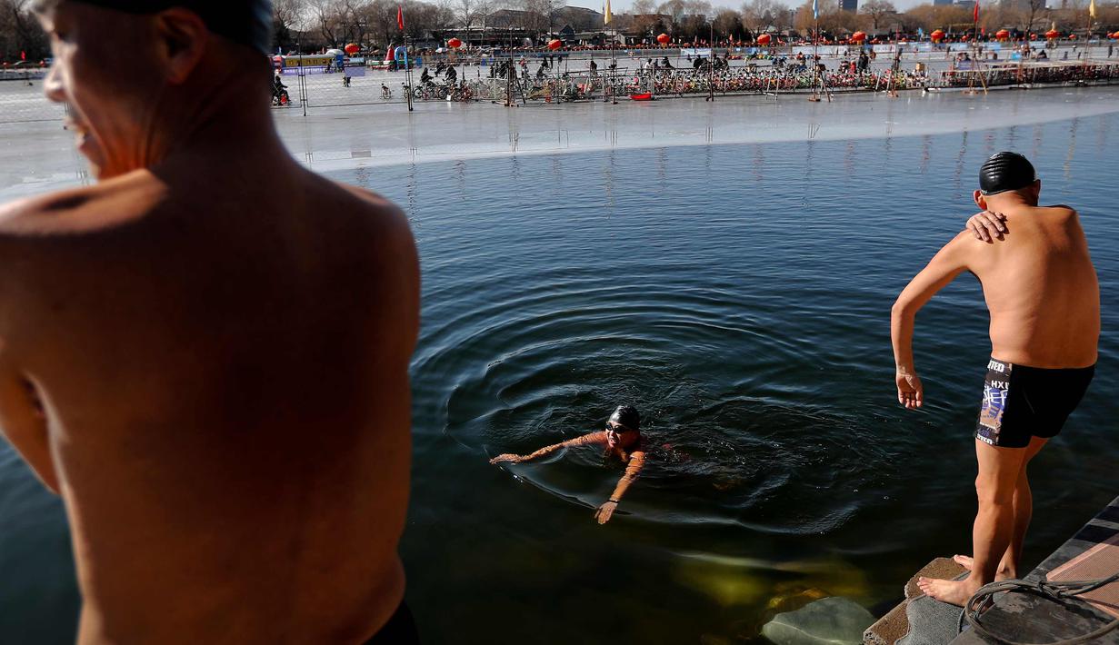 Sejumlah pria berenang di Danau Shichahai yang setengah beku di Beijing, (24/1). Menurut beberapa penduduk setempat, berenang di air dingin baik untuk kesehatan. (AP Photo / Andy Wong)