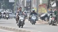 Pengendara sepeda motor tanpa mengenakan helm dan masker melintas di Jalan Pasar Minggu, Jakarta, Rabu (8/4/2020). Organisasi Kesehatan Dunia (WHO) telah merekomendasikan agar menggunakan masker saat berada di tempat umum demi memutus mata rantai penyebaran virus Corona. (merdeka.com/Iqbal Nugroho)